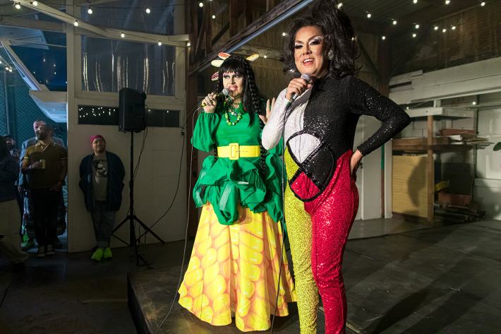 two Indigenous drag queens stand onstage