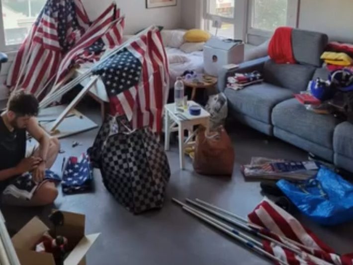 a slightly cluttered room full of American flags, some on the ground