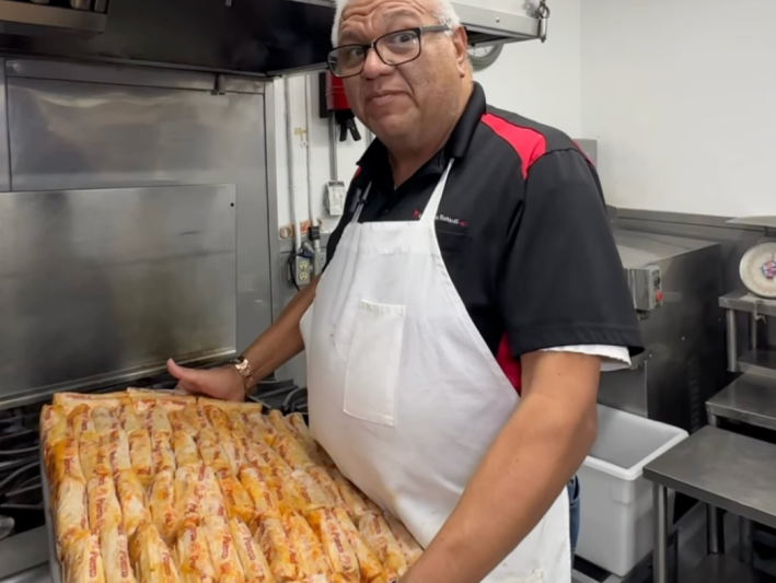 a man holds a tray of tamales
