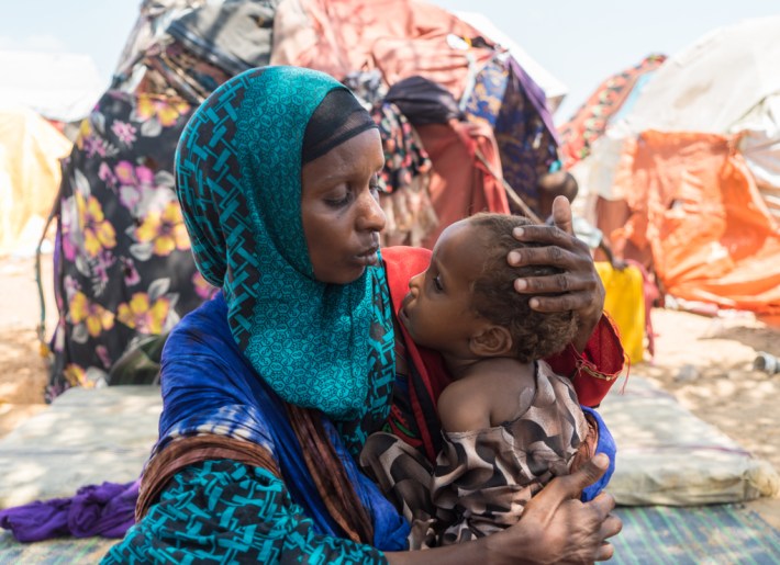 a woman wearing a head covering embraces her young child