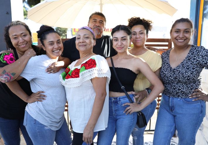 Family of six women and one man posing together smiling