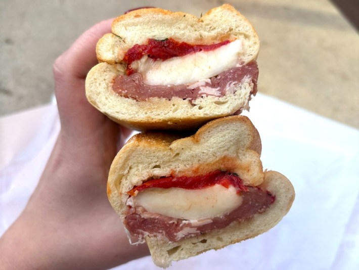 a cross-section of a sandwich with prosciutto, fresh mozzarella, tomato confit, and basil