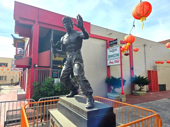 A seven-foot statue of Bruce Lee, who had a martial arts school in Chinatown, in front of signage for legendary Grand Star Jazz Club.