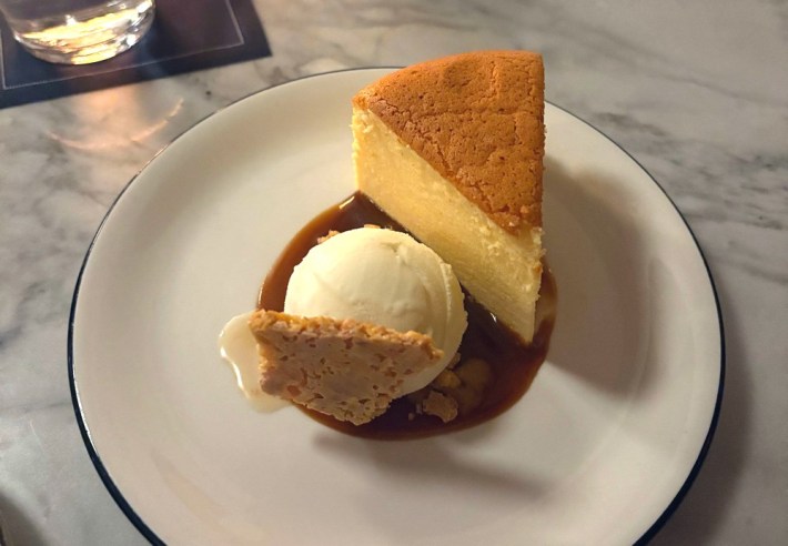 a slice of cheesecake next to a scoop of ice cream on a plate