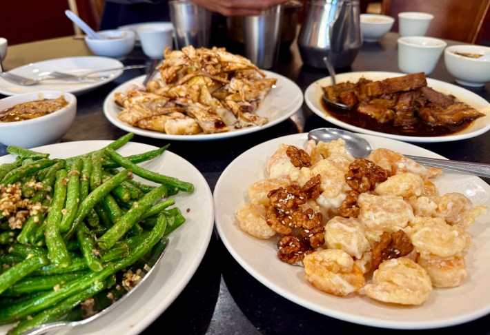 various platters of Chinese food on a table