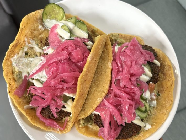 two tacos on corn tortillas with falafel and pickled cabbage