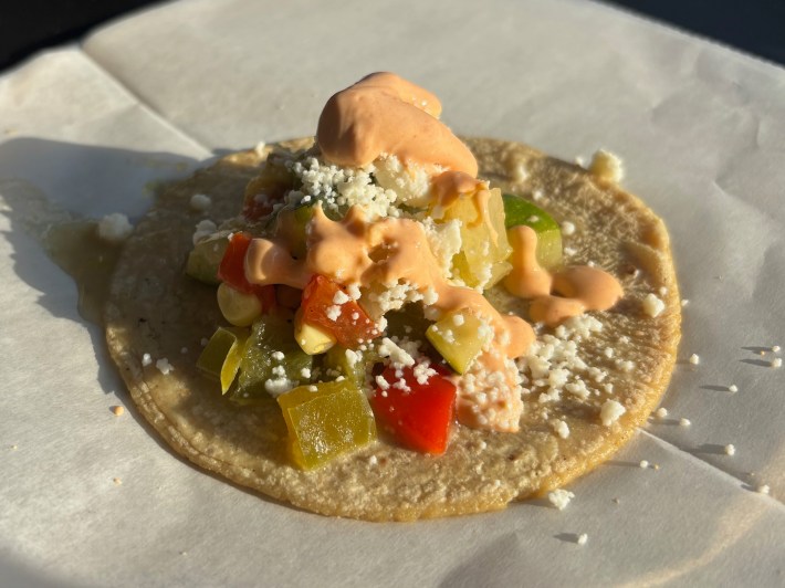 a corn tortilla with squash, corn, and crema on it