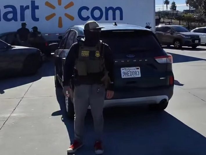 a masked agent in a Walmart parking lot