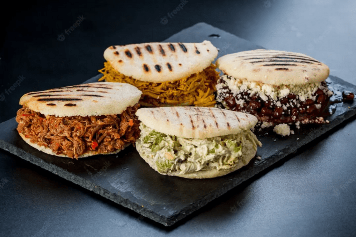 Four different arepas on a slate board
