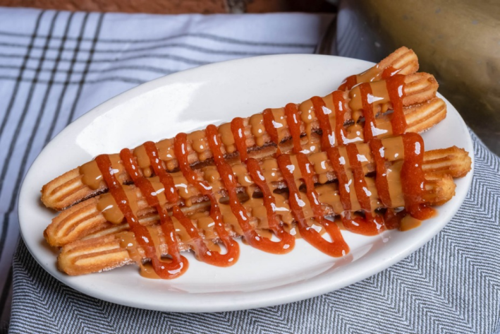 Dulce de lechedrizzled churros on a white plate
