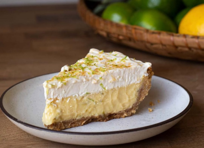A slice of key lime pie with passionfruit on a white plate.