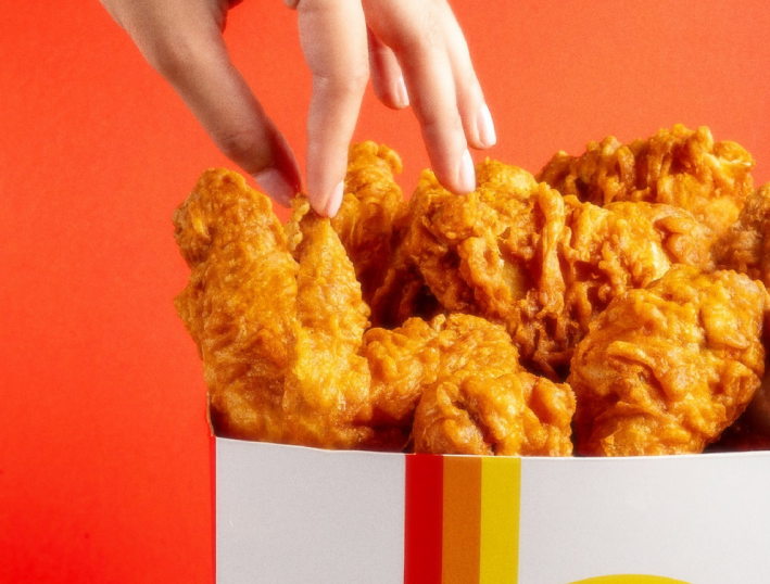 A hand picks a chicken tender from a white bag