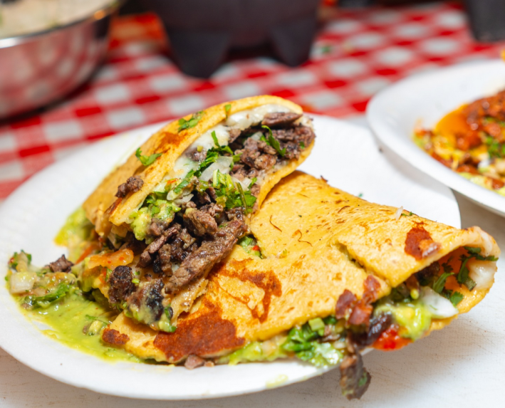 Quesadillas piled n a plate with meat coming out and a red salsa on top