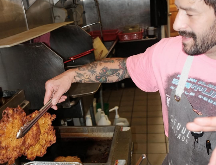 A chef, pulling a large piece of fried baccala from a deep-fryer