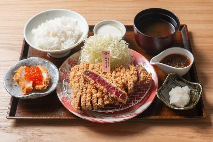 beef gyu-katsu on a plate that is on a tray with rice, scallop and ikura, and sauces