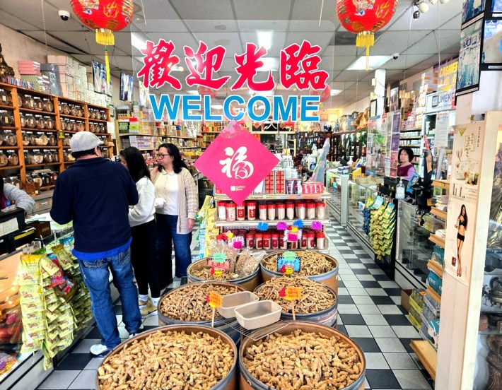 A Chinese herbal medicine shop with barrels of ginseng, customers, and tile floors