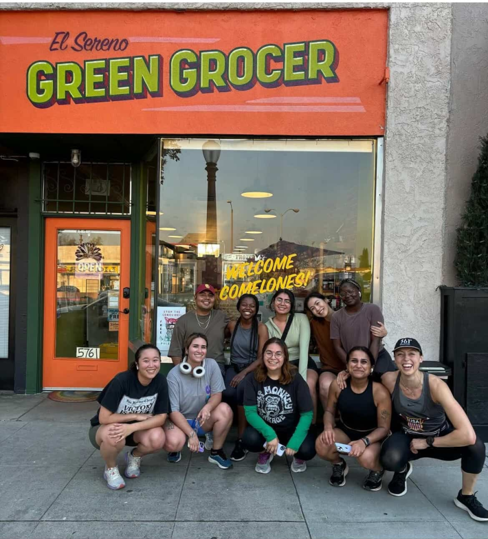 10 people pose outside of a storefront