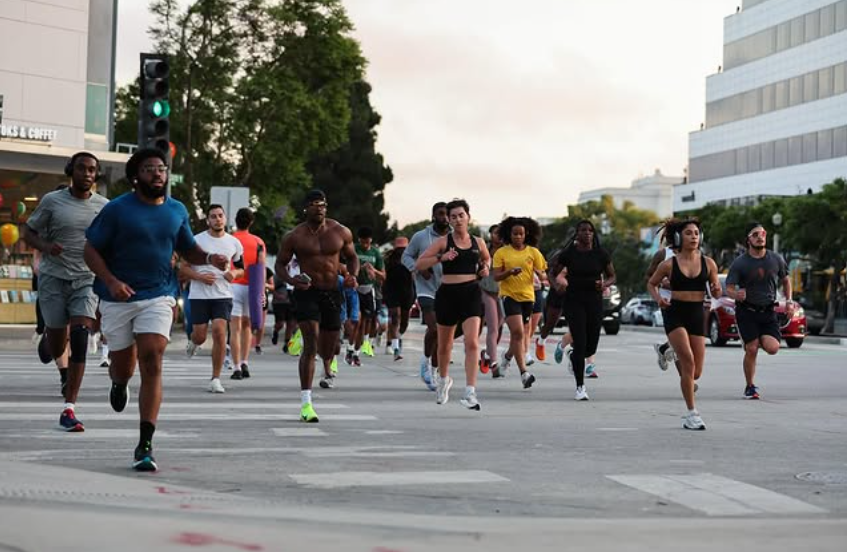 a crowd of people in athletic wear running on a city street