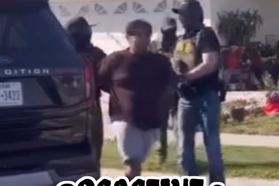 three masked agents around a man in shorts and a t-shirt