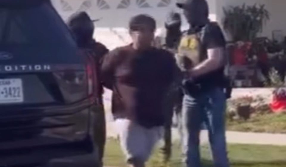 three masked agents around a man in shorts and a t-shirt