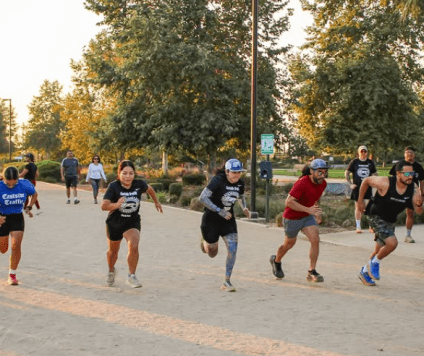 five people running on a park path