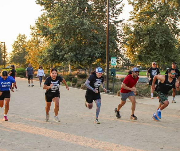 five people running on a park path