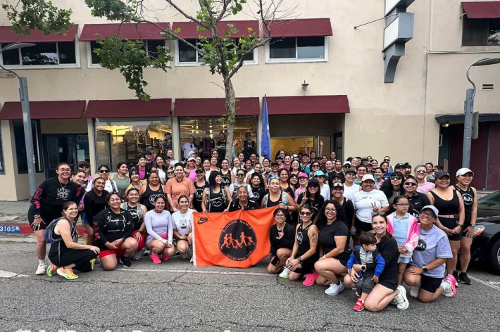 a crowd of women holding an orange flag with the "Running Mamis" logo