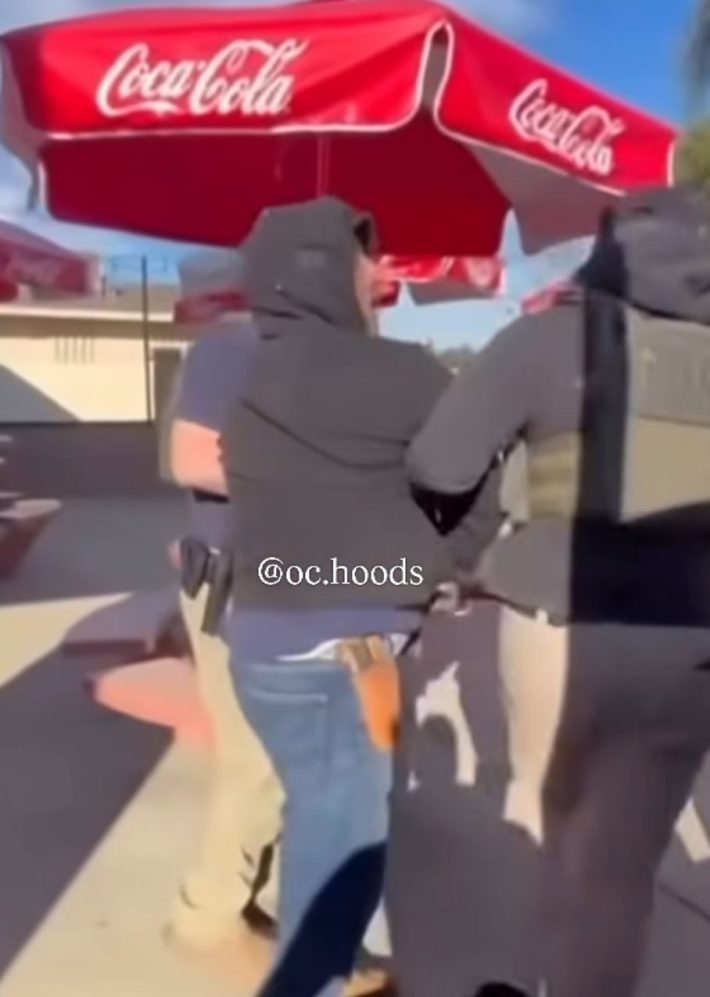 a man is held by the arm by a federal agent