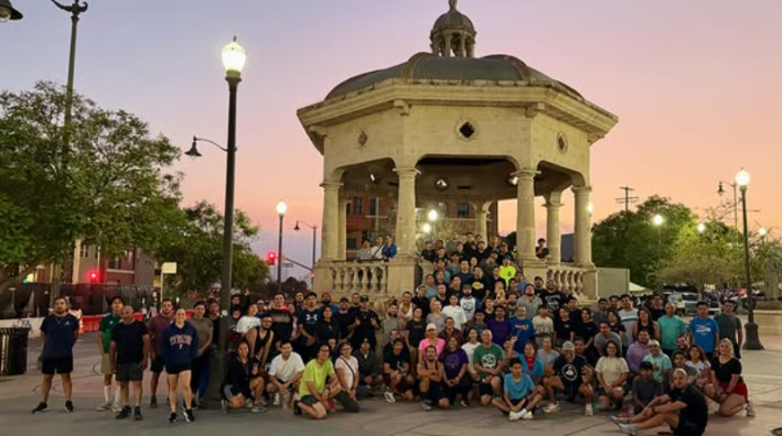 a crowd of runners in front of a stone gazebo