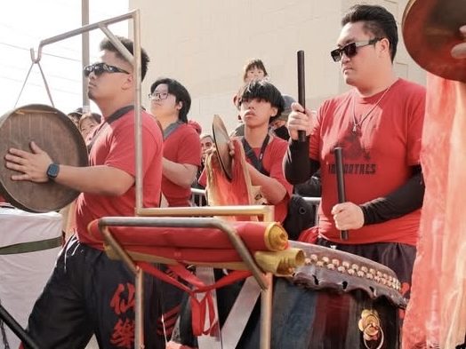 Four musicians play the drums and cymbals in a parade