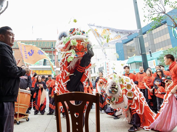 a lion dancer throws lettuce from the mouth opening of the costume