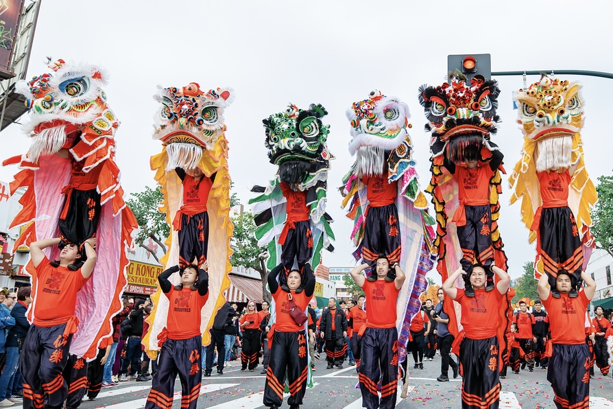 Six dancers wear lion heads as they each stand on another dancer’s shoulders.