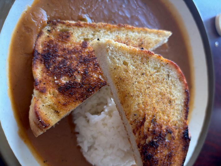 a bowl of etoufee with rice and bread