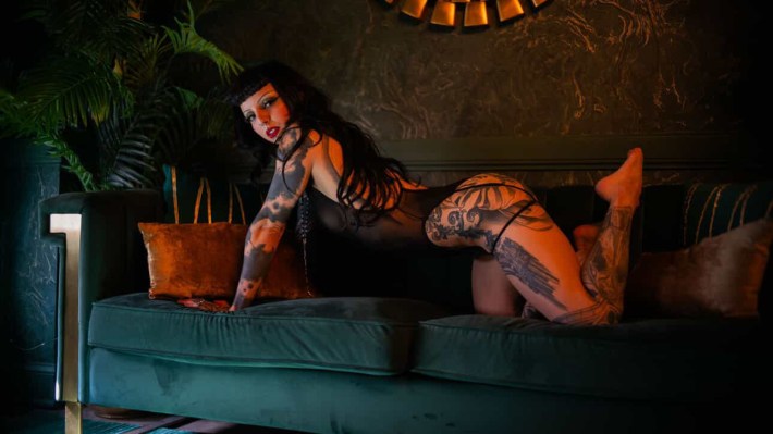 a woman poses on a couch in lingerie