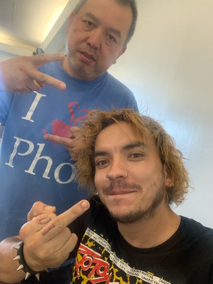 a man poses with a peace sign next to a man with a middle finger