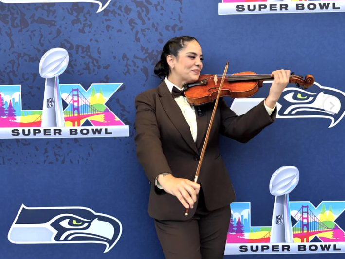 a woman in a suit plays the violin