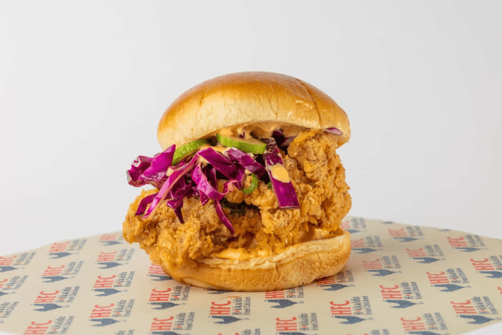 Fried chicken sando with purple cabbage and pickles on a brioche burger bun