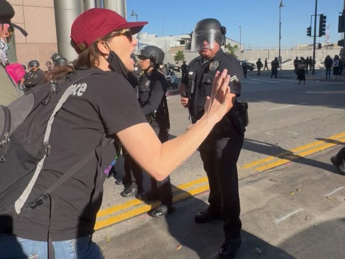 a woman pleads in front of a line of officers