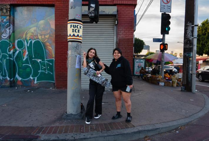 two people on a street corner pointing at a FUCK ICE bead bomb