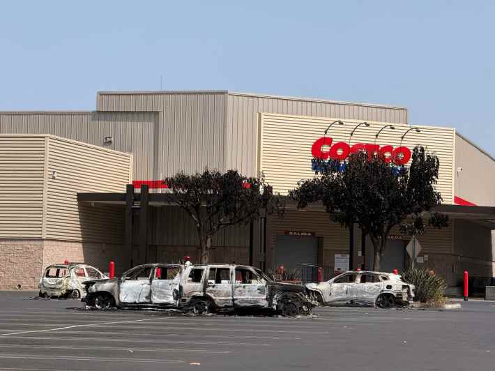 a Costco building with burnt vehicles in the parking lot