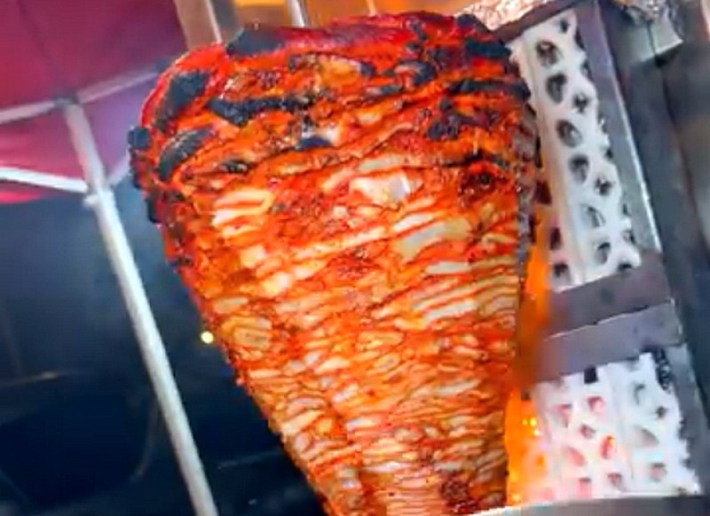 A big trompo of al pastor cooking