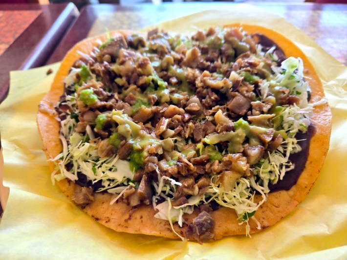 A tostada spread with black beans, cabbage, and steamed cabeza de puerco.