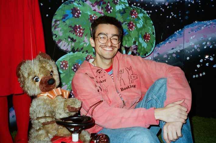 a man wearing glasses next to a bear puppet