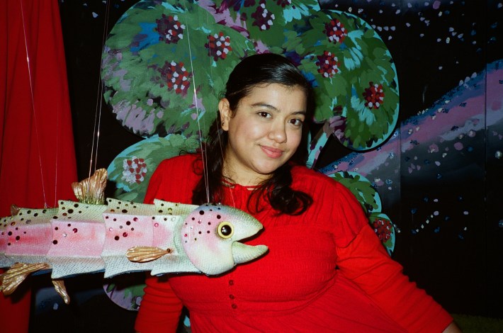 a woman in red posing with a fish puppet
