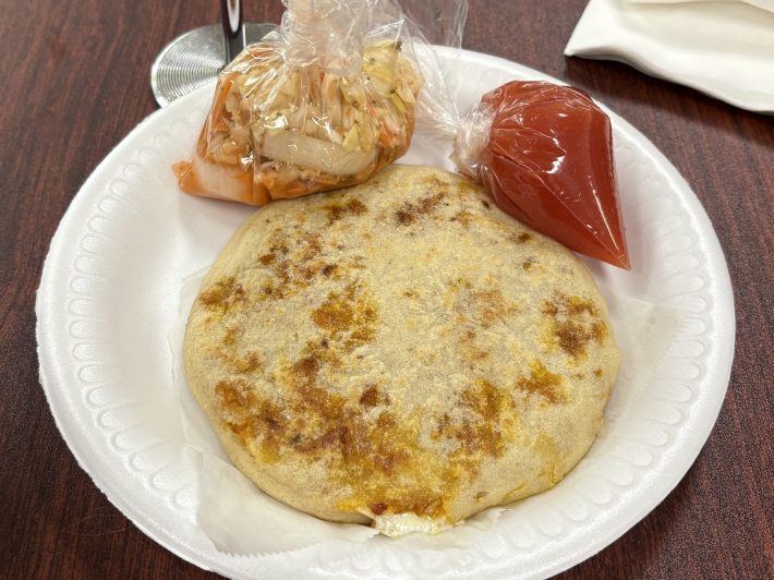 a plate with one pupusa, salsa, and slaw