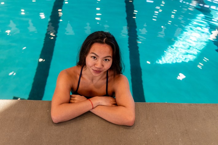 a young woman poses from inside a pool