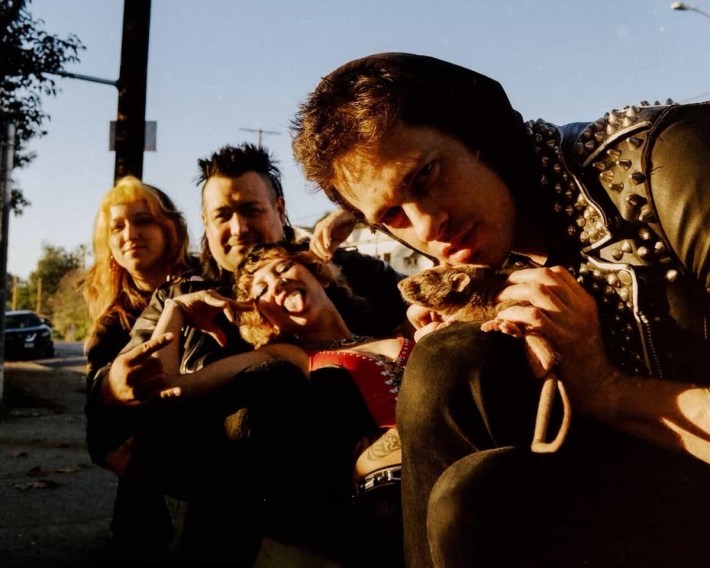 a band posing together on a street