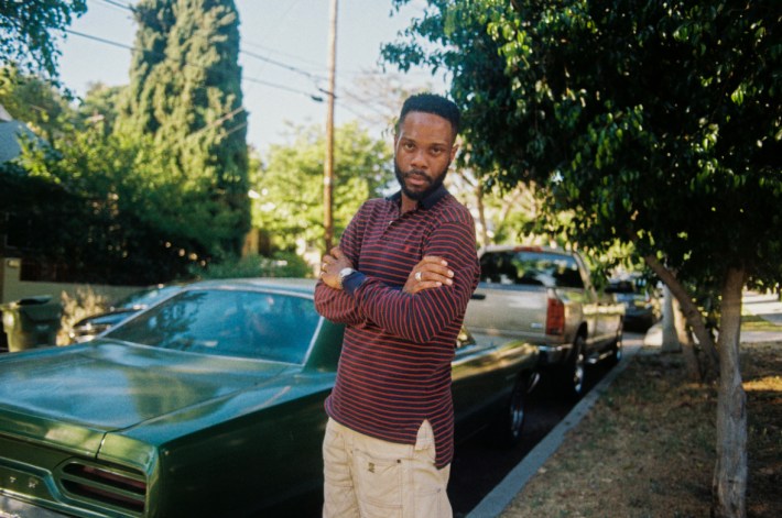 a man poses in front of a car