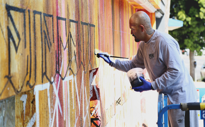 a man painting a wall outside