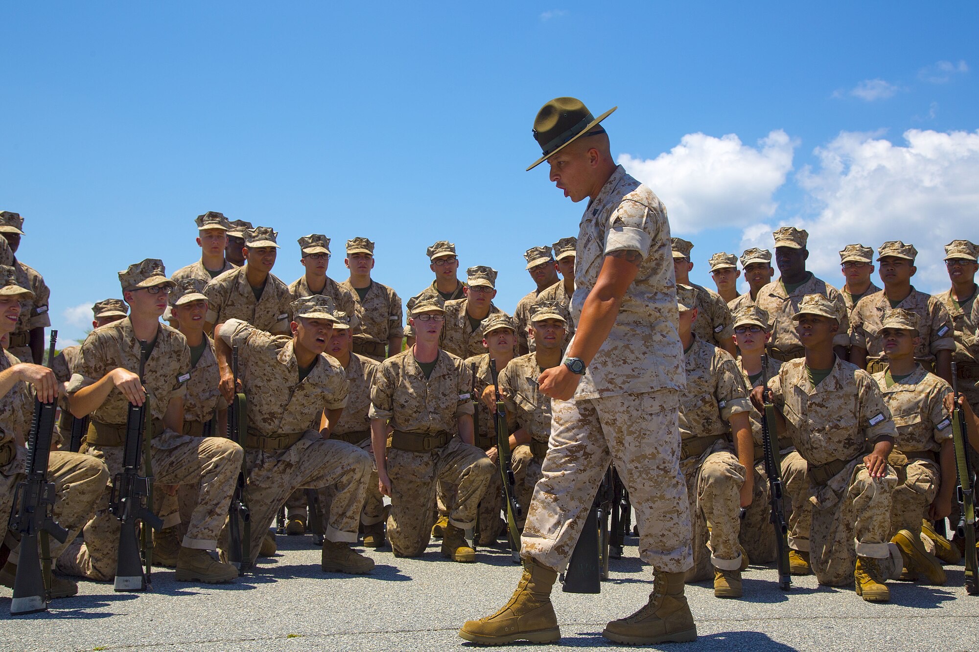 U.S. Marine Staff Sgt. Jeremy Bolanos, drill master, 1st Recruit Training Battalion, Recruit Training Regiment, Marine Corps Recruit Depot Parris Island, demonstrates a drill movement to recruits aboard Marine Corps Recruit Depot, Parris Island, S.C., May 13, 2014. Photo via Aneshea Yee / wikicommons.